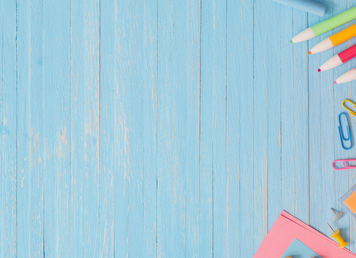 Assorted stationery items including pens, paper clips, and colored paper arranged on the top right corner of a blue wooden surface.